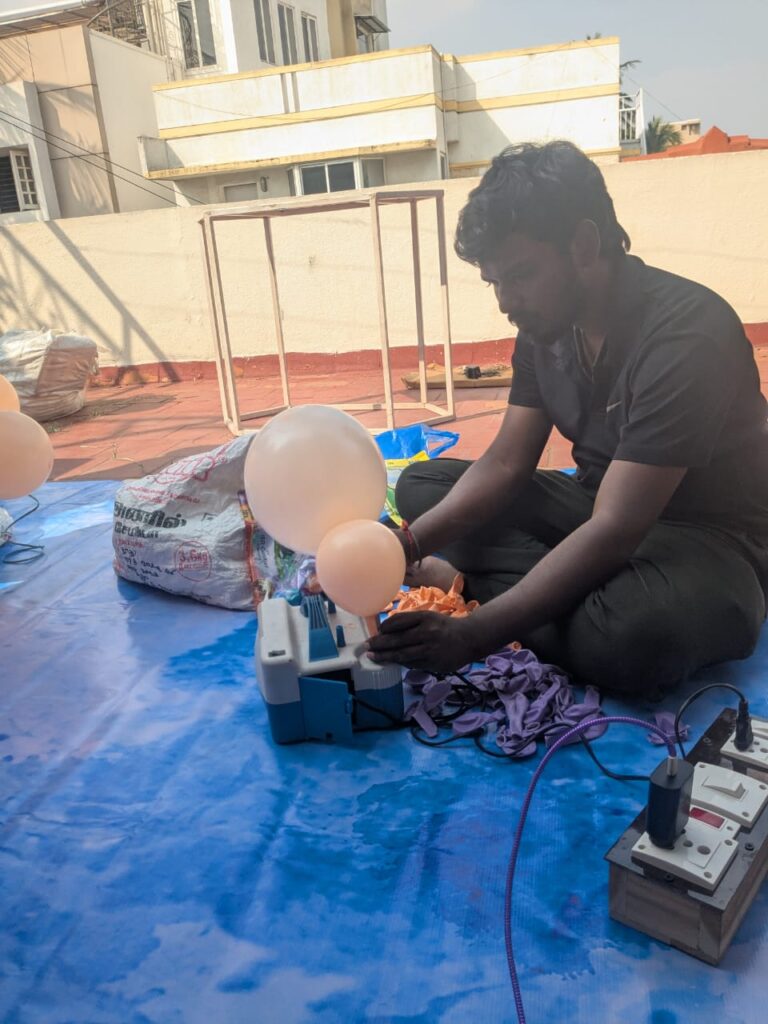Decorator inflating balloons during setup of butterfly-themed terrace birthday decoration in Chennai.