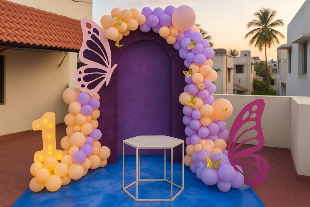Butterfly-themed first birthday decoration setup on a terrace in Arumbakkam, Chennai, featuring pastel balloons, butterfly cutouts, and a purple arch backdrop.