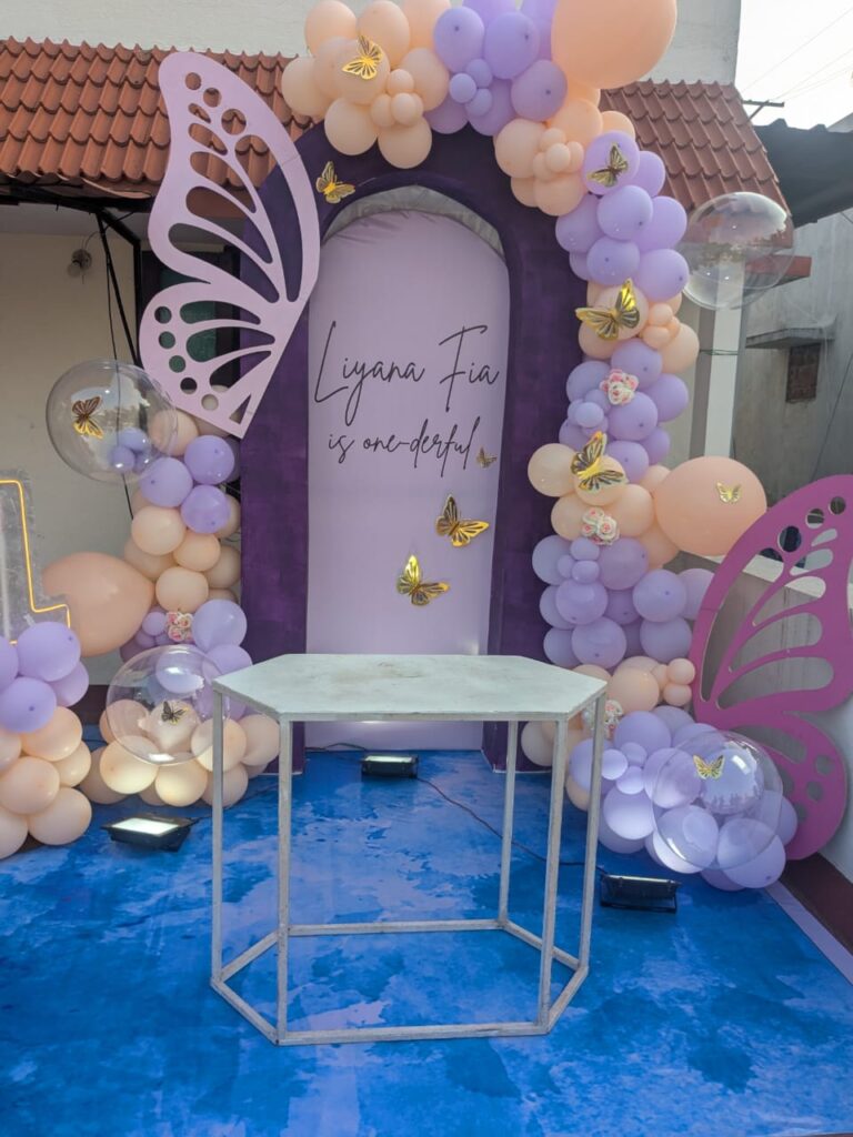 Pastel lavender and peach balloon garland with butterfly cutouts for terrace birthday setup in Chennai.