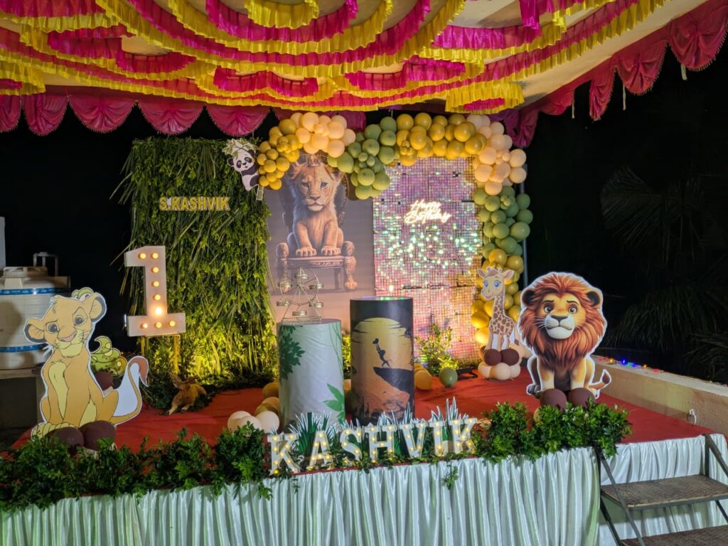  Simba character decoration placed in front of jungle-themed birthday stage for baby Kashvik.
