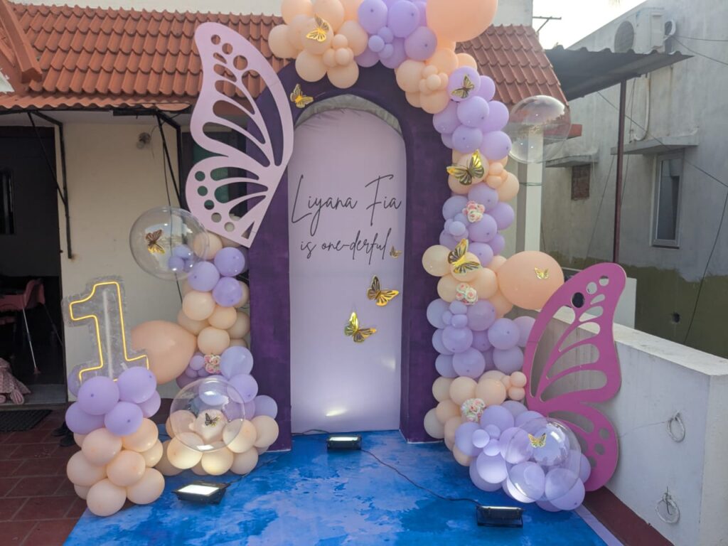 Terrace backdrop with purple arch and butterfly wings for baby Liyana Fia’s first birthday decoration.