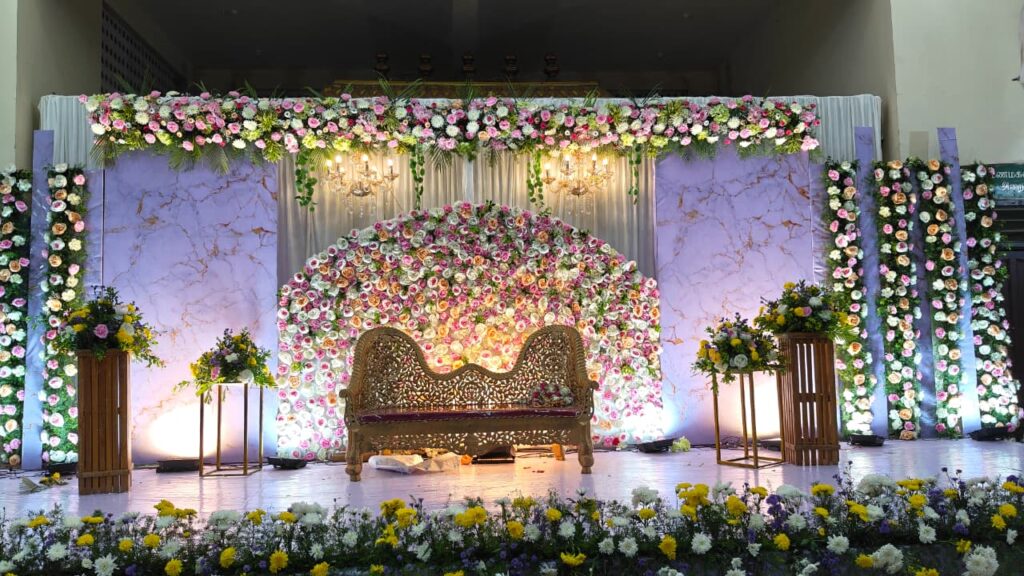 Pastel floral wedding stage decoration with royal sofa and chandelier lighting at K C M Mahal Auroville Pondicherry
