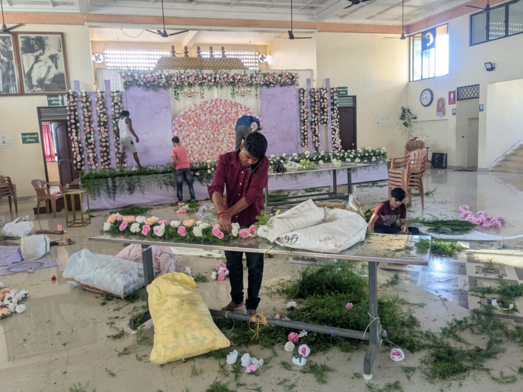 Behind the scenes wedding stage floral backdrop installation at K C M Mahal Auroville