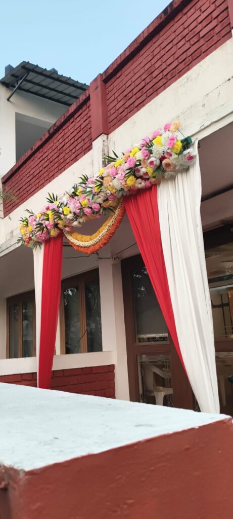 Floral entrance arch decoration with red and white drapes for Mehendi event